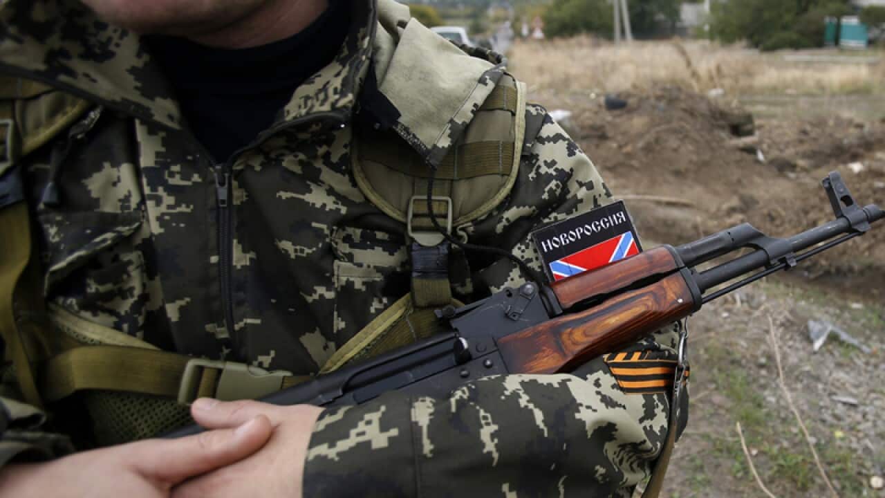 A Pro-Russian rebel guards a mass grave in Nyzhnya Krynka