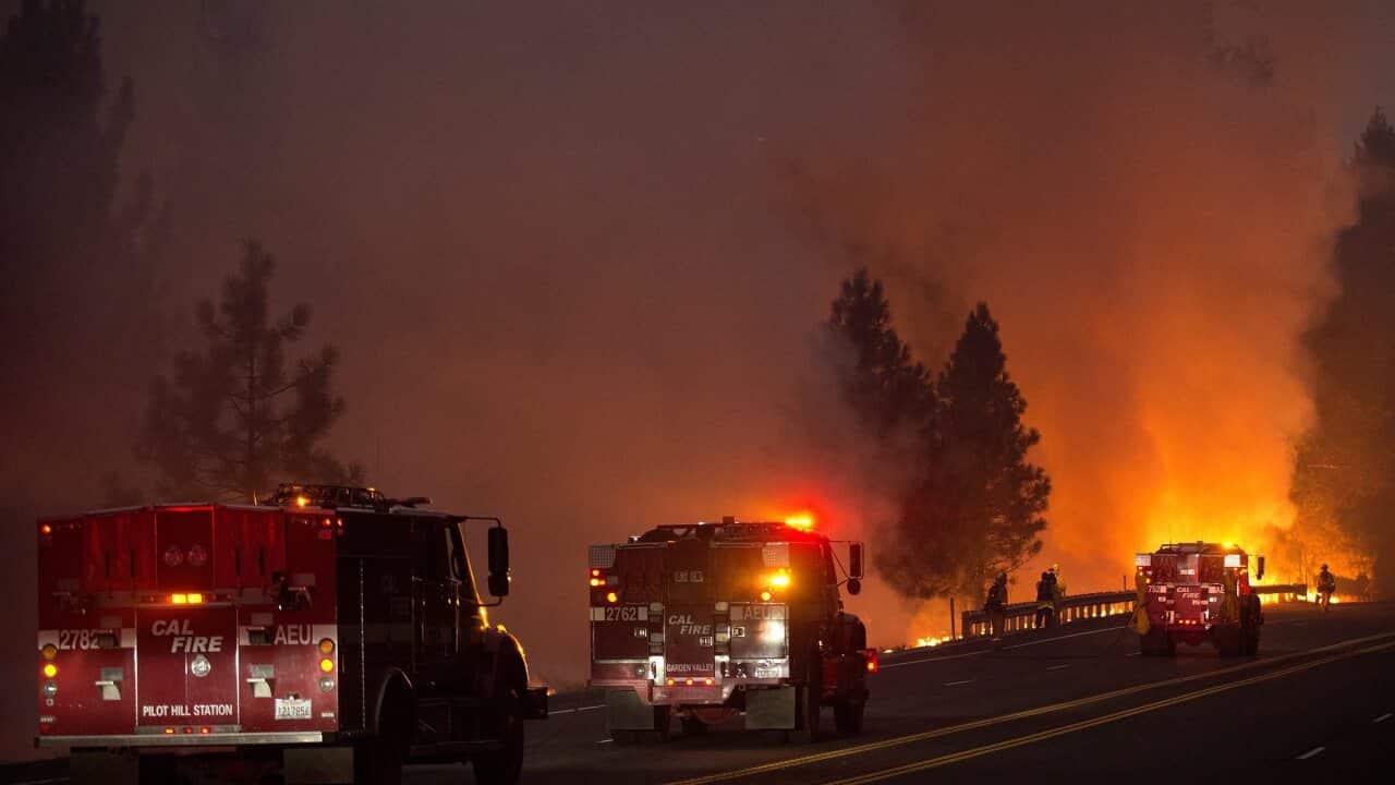 Fire engines back up firefighters conducting a controlled firing operation to create a wide fire break along US Route 50 near the town of Pollock Pines, California(AAP)
