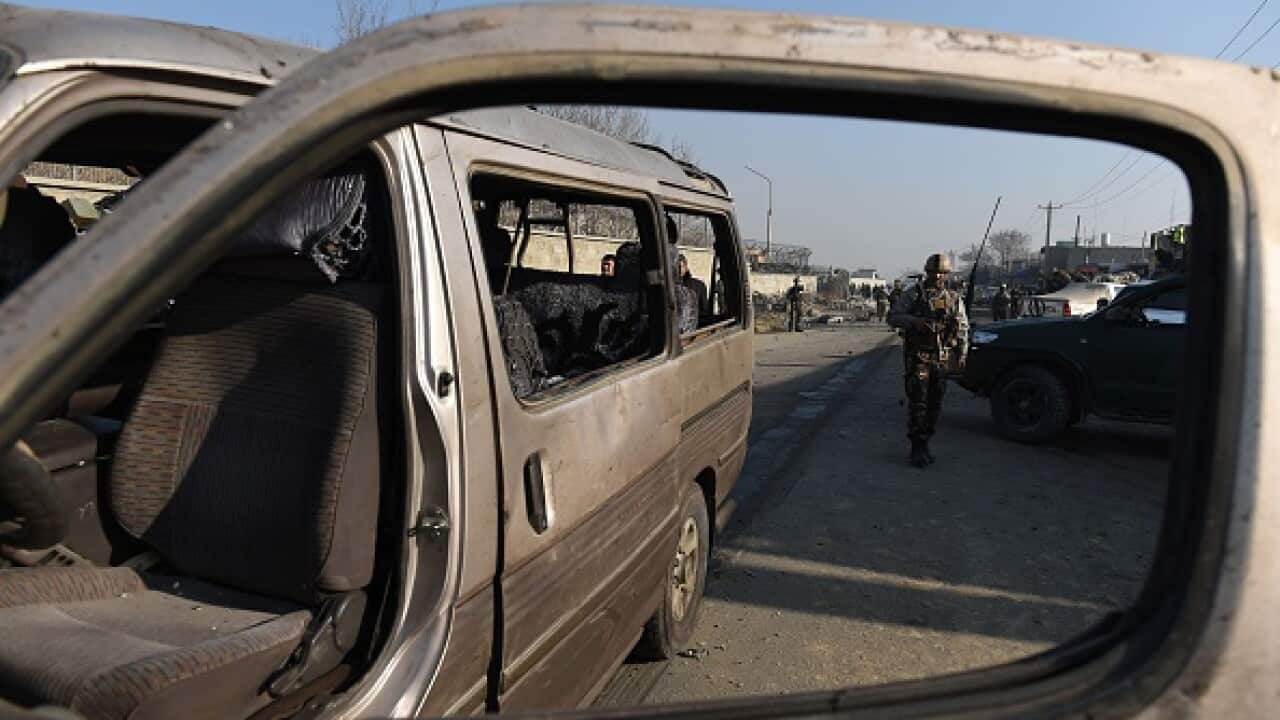 An Afghan security force member inspects the site of a suicide car bomb near the international airport in Kabul on December 28, 2015. A Taliban bomber
