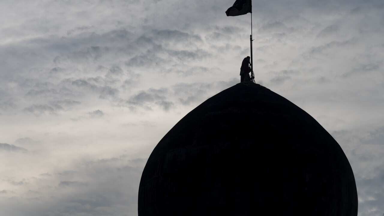 A Shia Muslim man erect flags on dome of an Imam Bara ahead