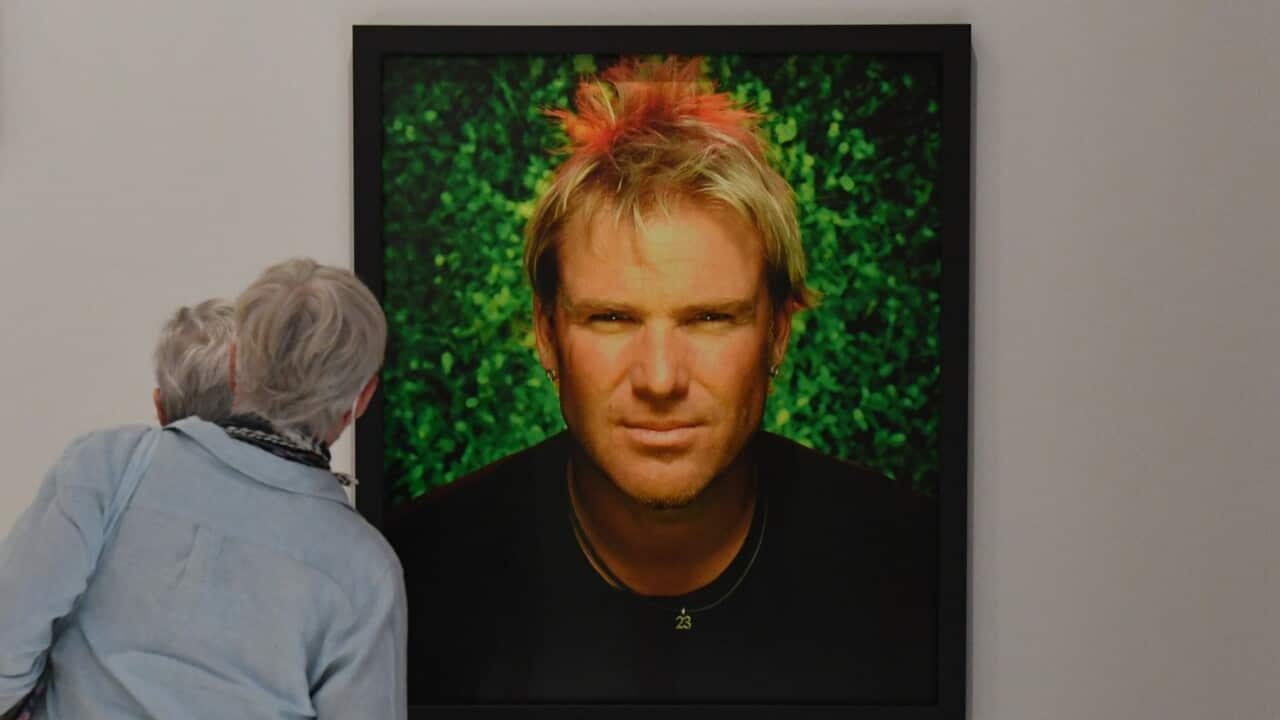 Members of the public look at a portrait of cricketer Shane Warne at an exhibition at the National Portrait Gallery in Canberra