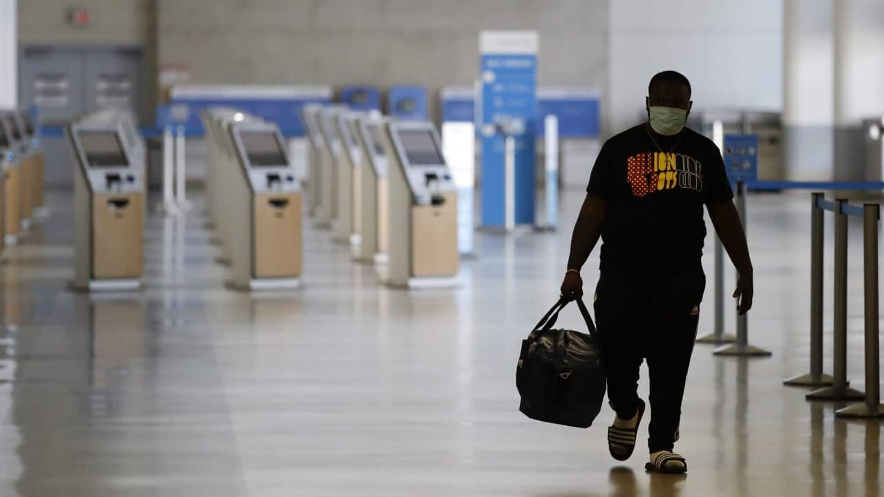 A traveler walks in a mostly empty American Airlines terminal at the Los Angeles International Airport in May, 2020.