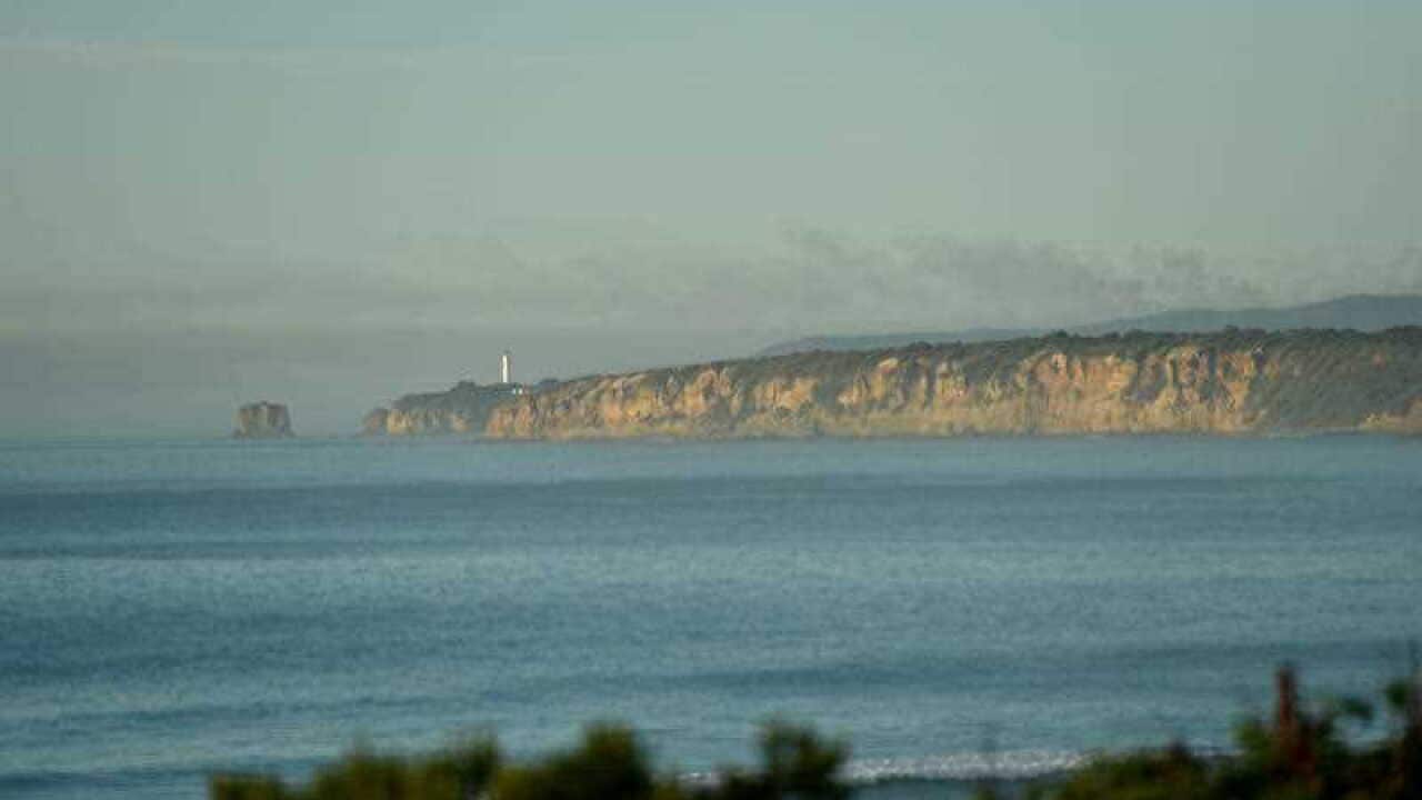 Smoke from the Otways bushfire rises over the Split Point Lighthouse on the Great Ocean Road in Aireys Inlet