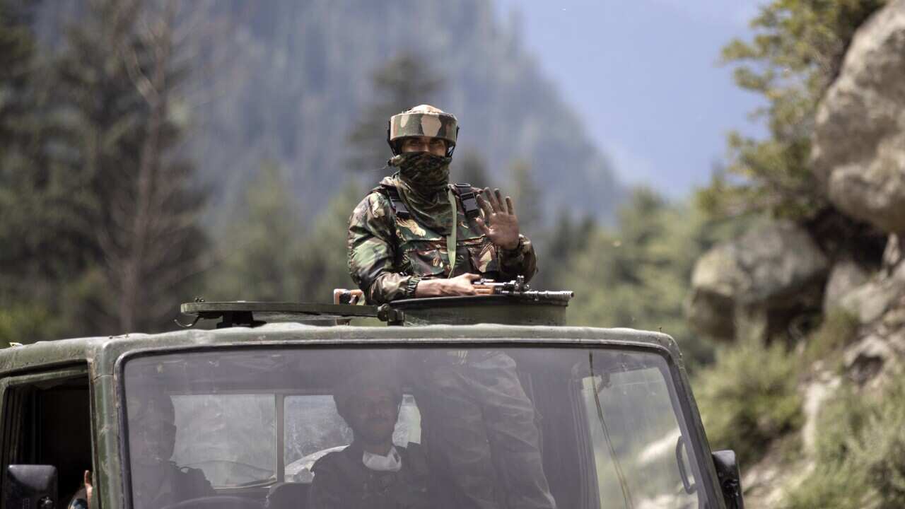 An Indian army soldier waves as their convoy moves.
