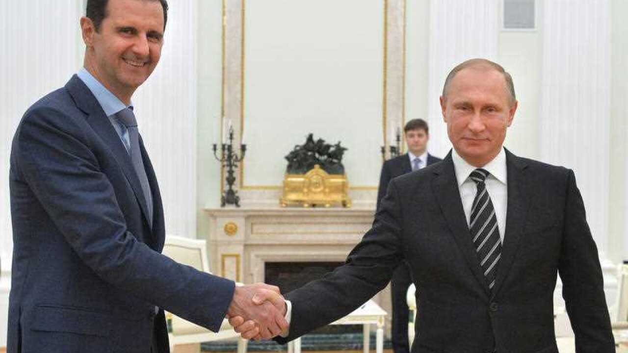 Russian President Vladimir Putin, center, shakes hand with Syrian President Bashar Assad.
