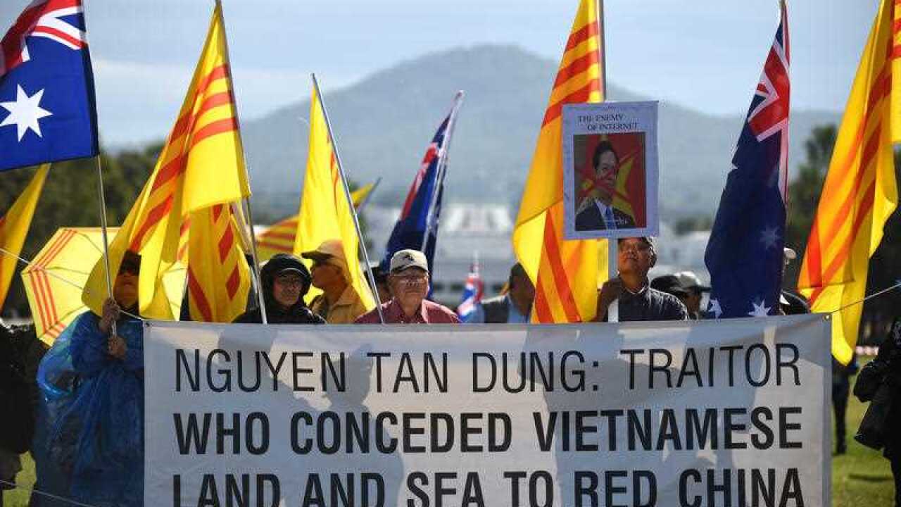 Demonstrators holding the flags of the former South Vietnam protest the visit of Vietnam's Prime Minister Nguyen Tan Dung to Parliament House in Canberra (AAP Image/Mick Tsikas)