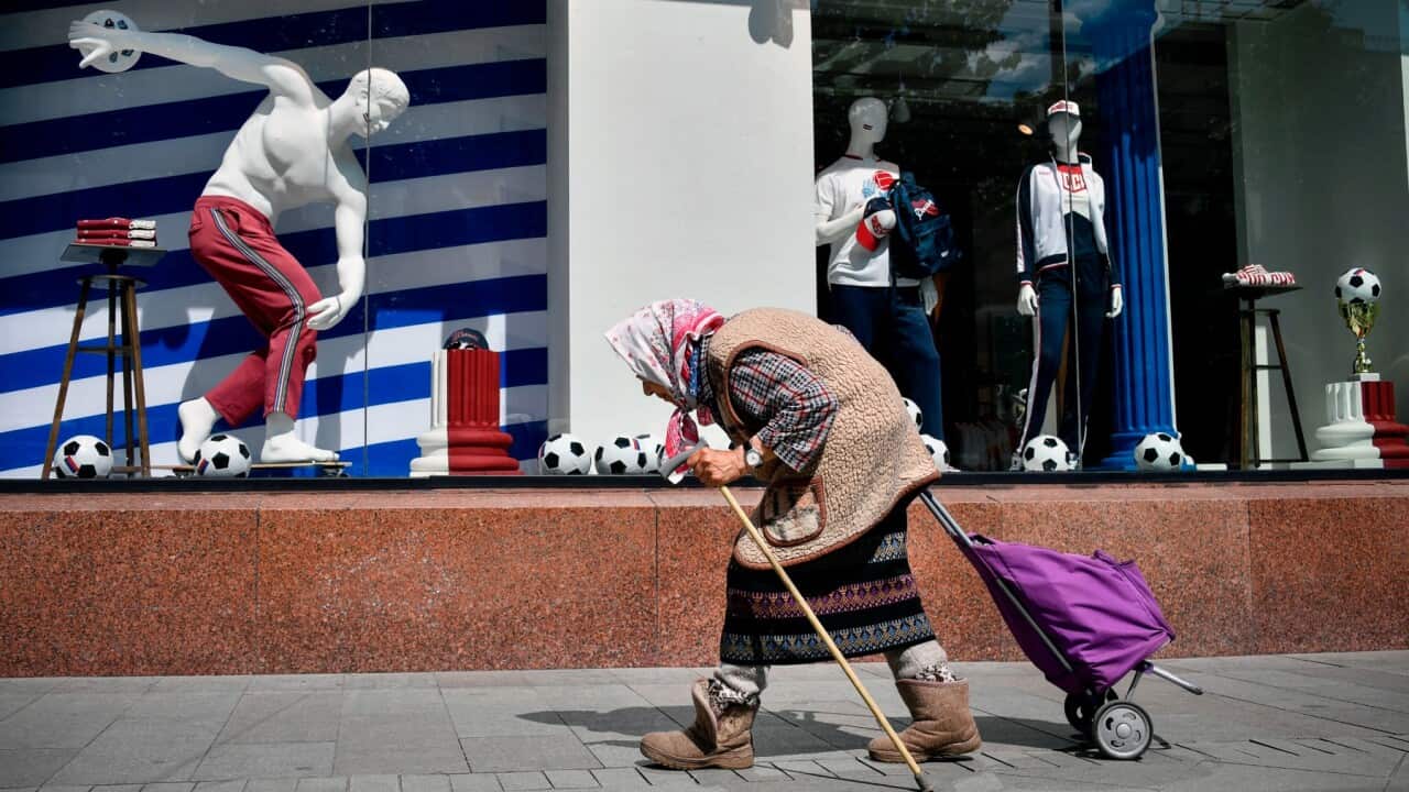 An elderly woman walks past a sports goods shop in Moscow on July 13, 2018, two days before the Russia 2018 World Cup final football match between France and Croatia
