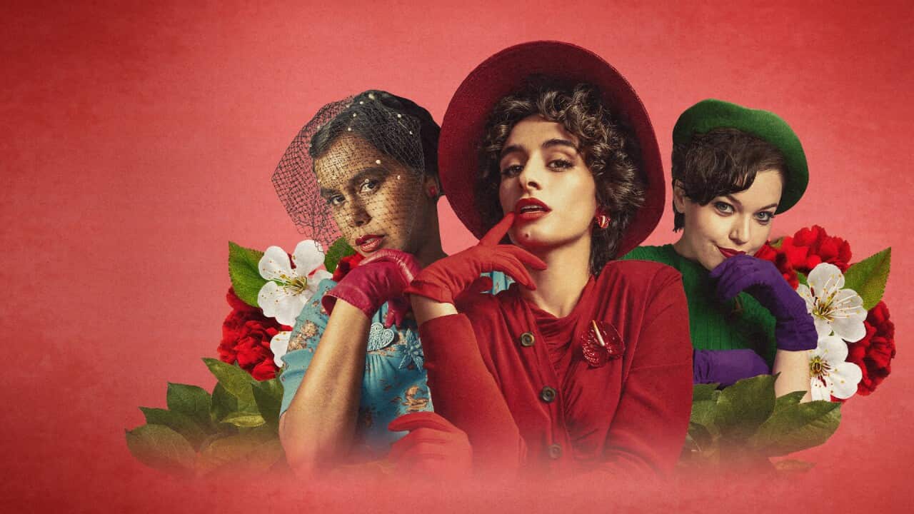 3 women in 1950s outfits pose surrounded by flowers