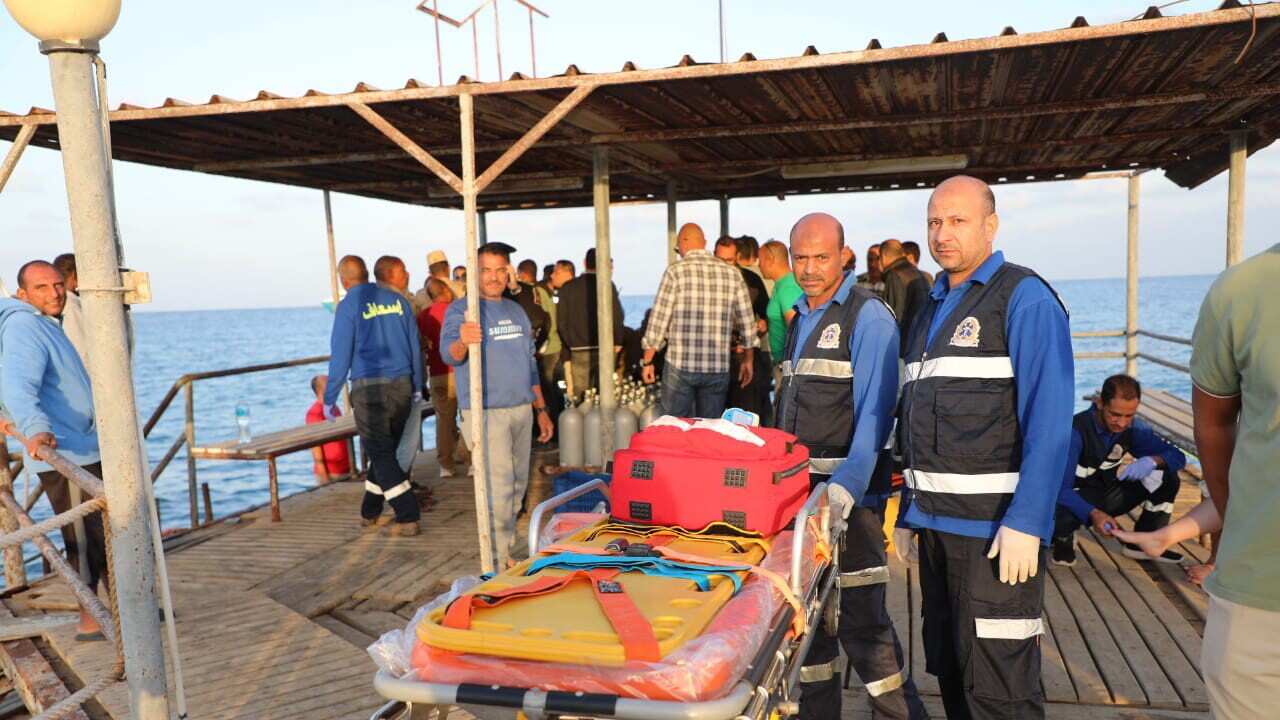 Medics stand with a stretcher on a jetty crowded with people