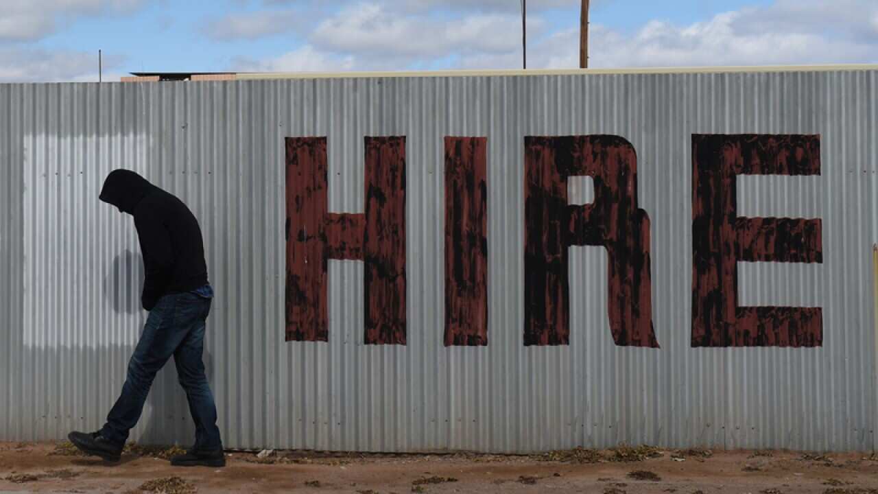 A man walks past a hand painted hire sign in Bourke
