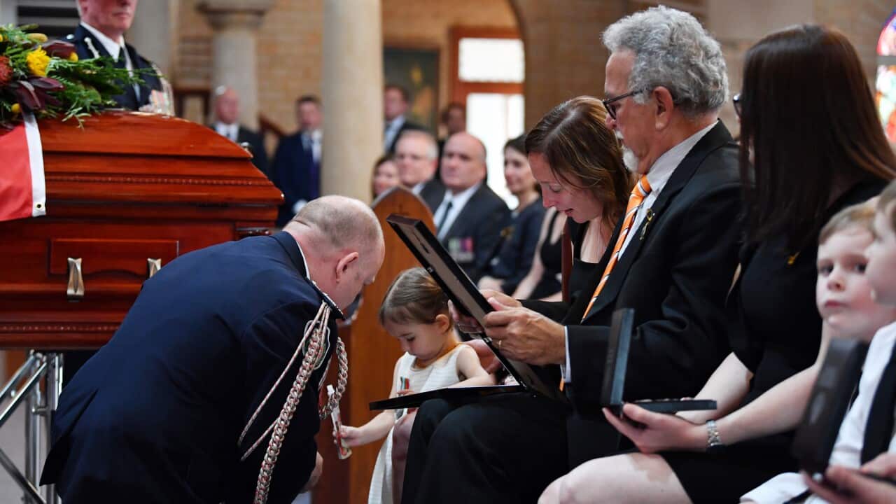 Charlotte O'Dwyer, the daughter of RFS volunteer Andrew O'Dwyer, receives her father's service medal from RFS Commissioner Shane Fitzsimmons