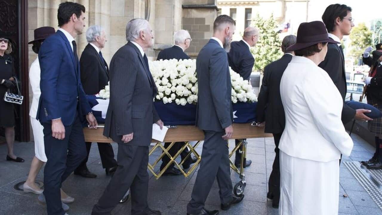The coffin of Ron Walker is lead away by pallbearers.