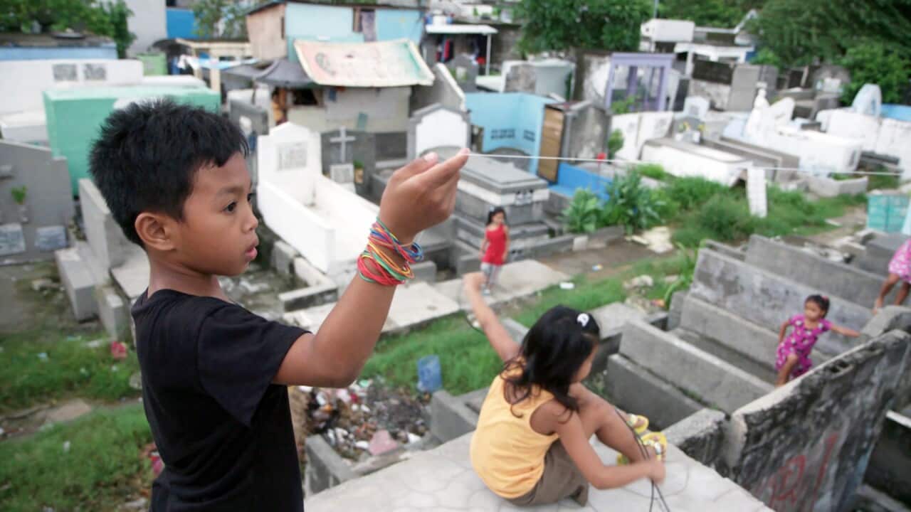 A child plays with a kite in Pasay City Cemetery.
