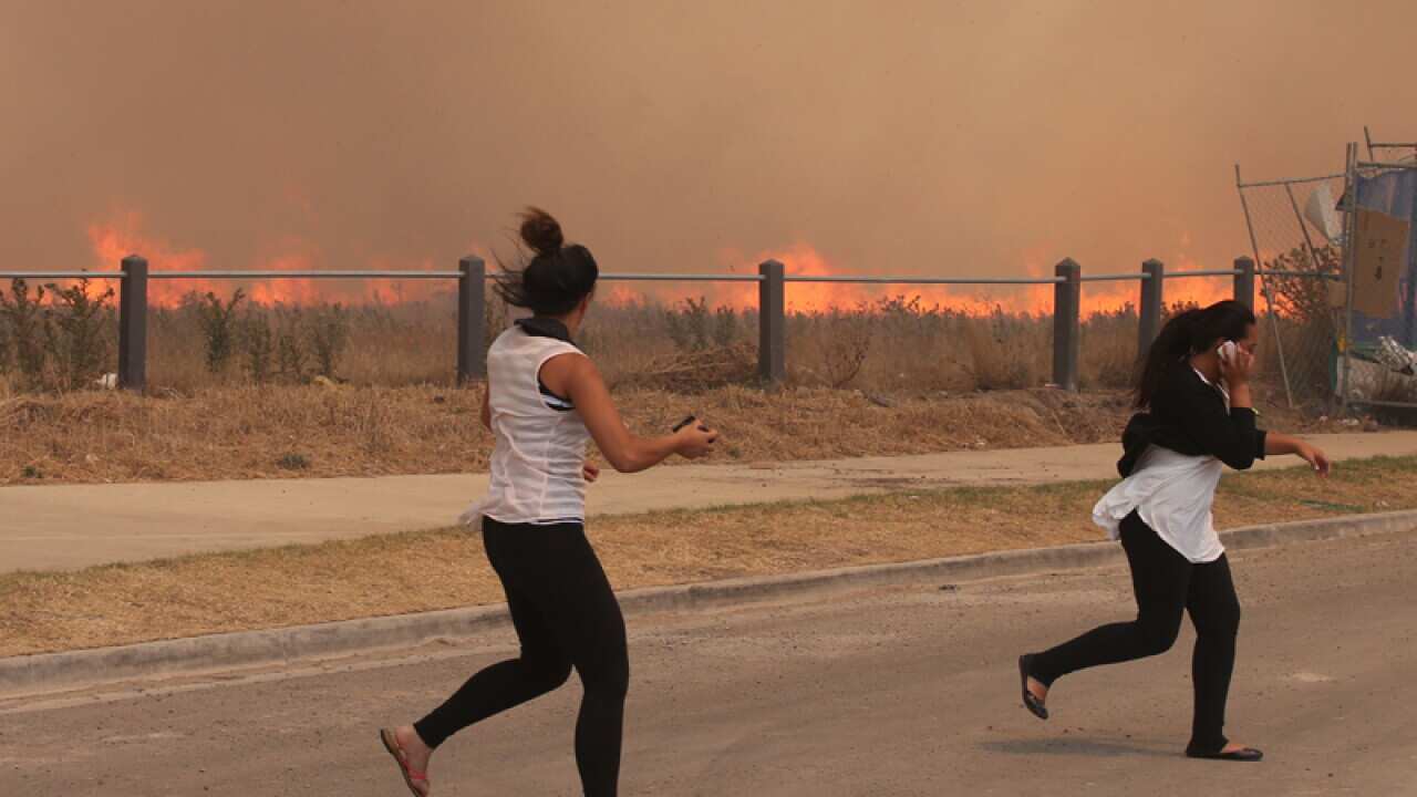 Residents run from a fast moving grass fire in Craigieburn