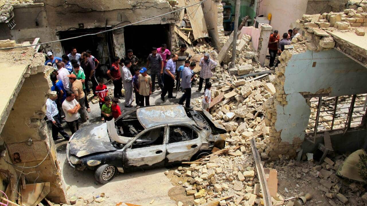 Iraqis inspect the site of a car bomb that exploded in a popular market in Baghdad - AAP.jpg