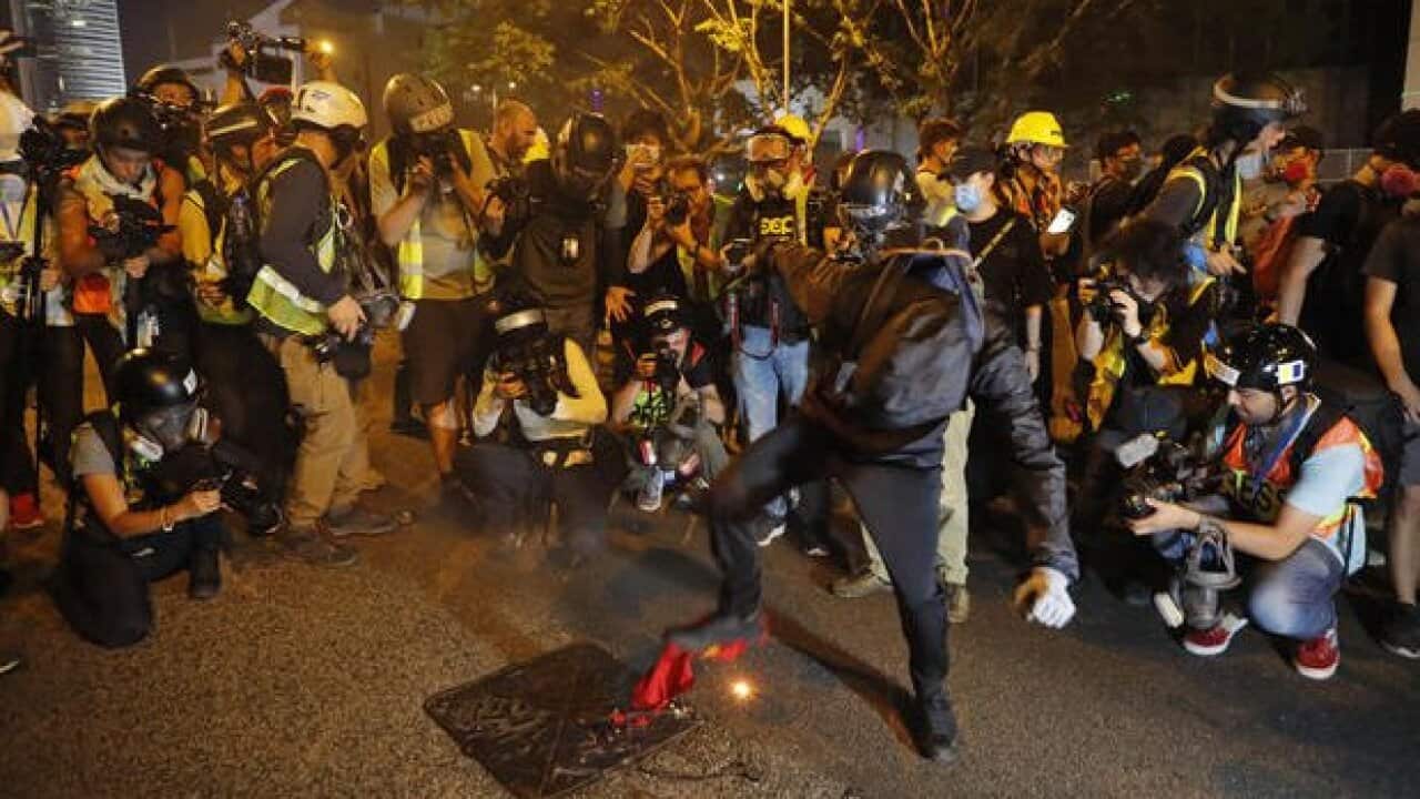 Black-clad protesters wearing goggles and mask stomps on a burning Chinese flag in Hong Kong, Saturday, September 28, 2019.