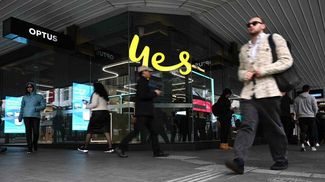 People walking past an Optus storefront