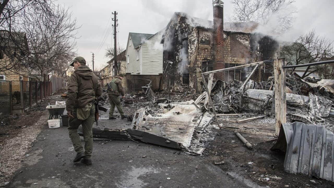 Ukrainian servicemen walk by fragments of a downed aircraft in Kyiv.