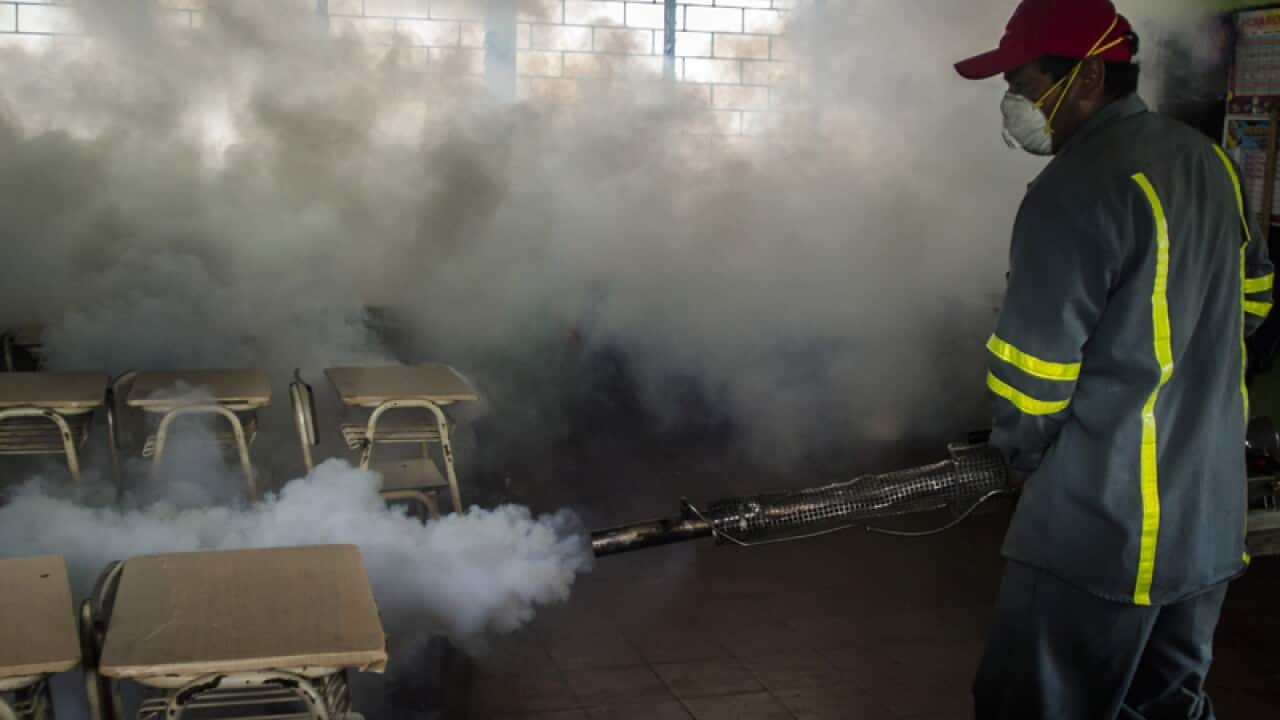 A city worker fumigates a classroom in El Salvador