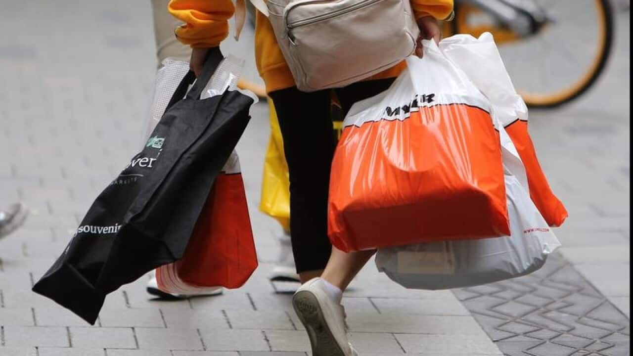 A shopper is seen carrying shopping bags.