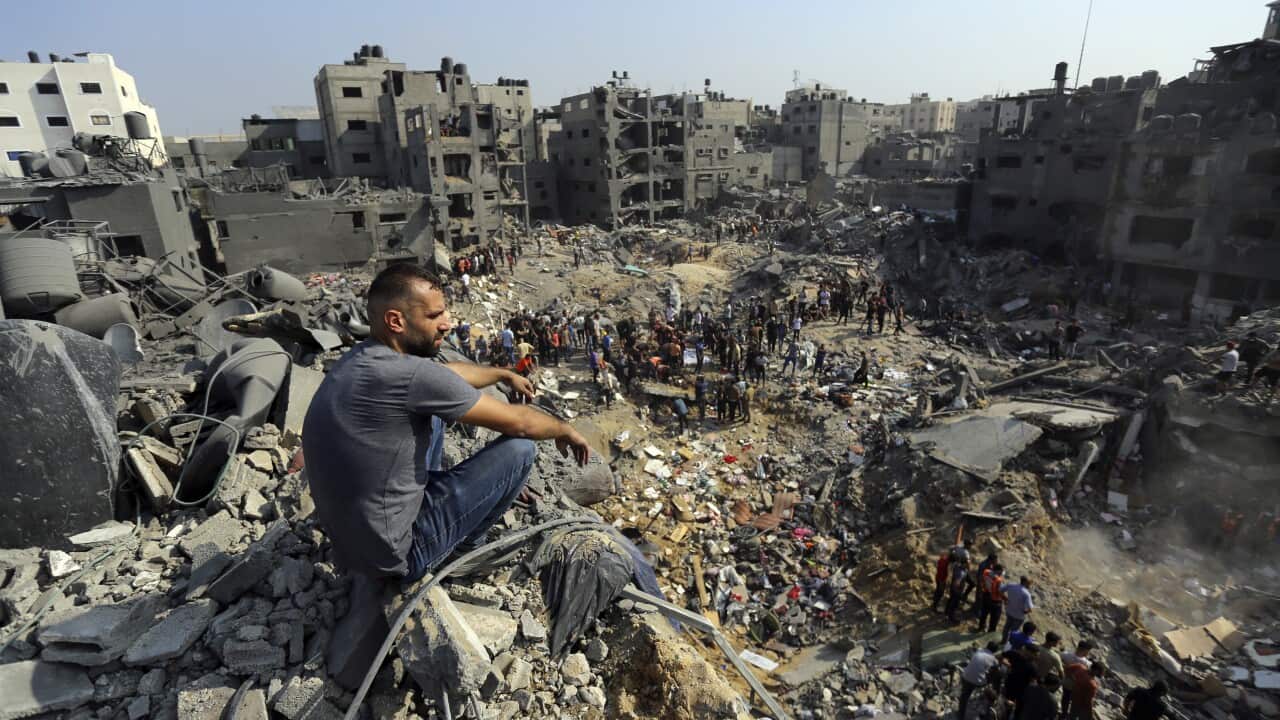A man sitting in a pile of rubble looking down at another crowd of men.
