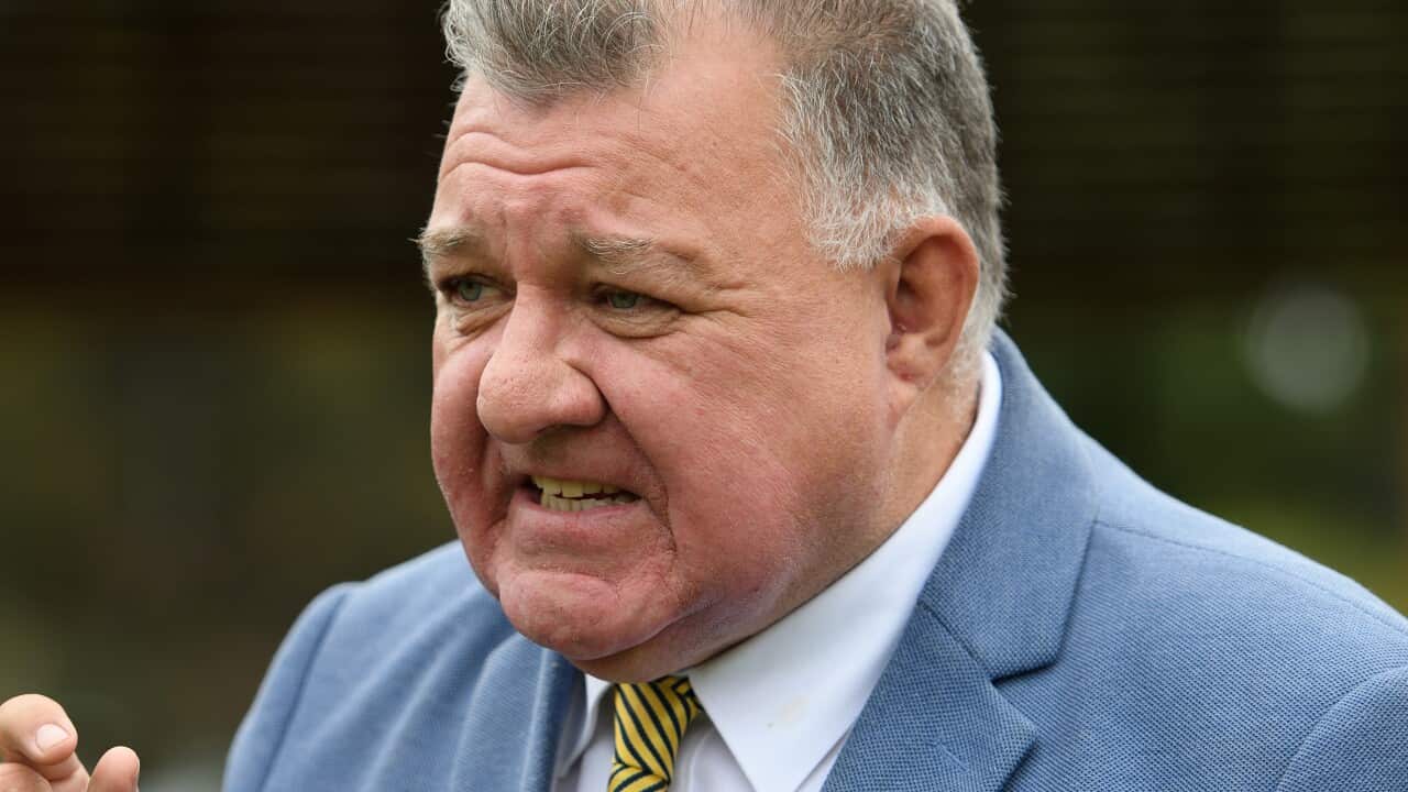 A man wearing a suit and tie who is speaking.