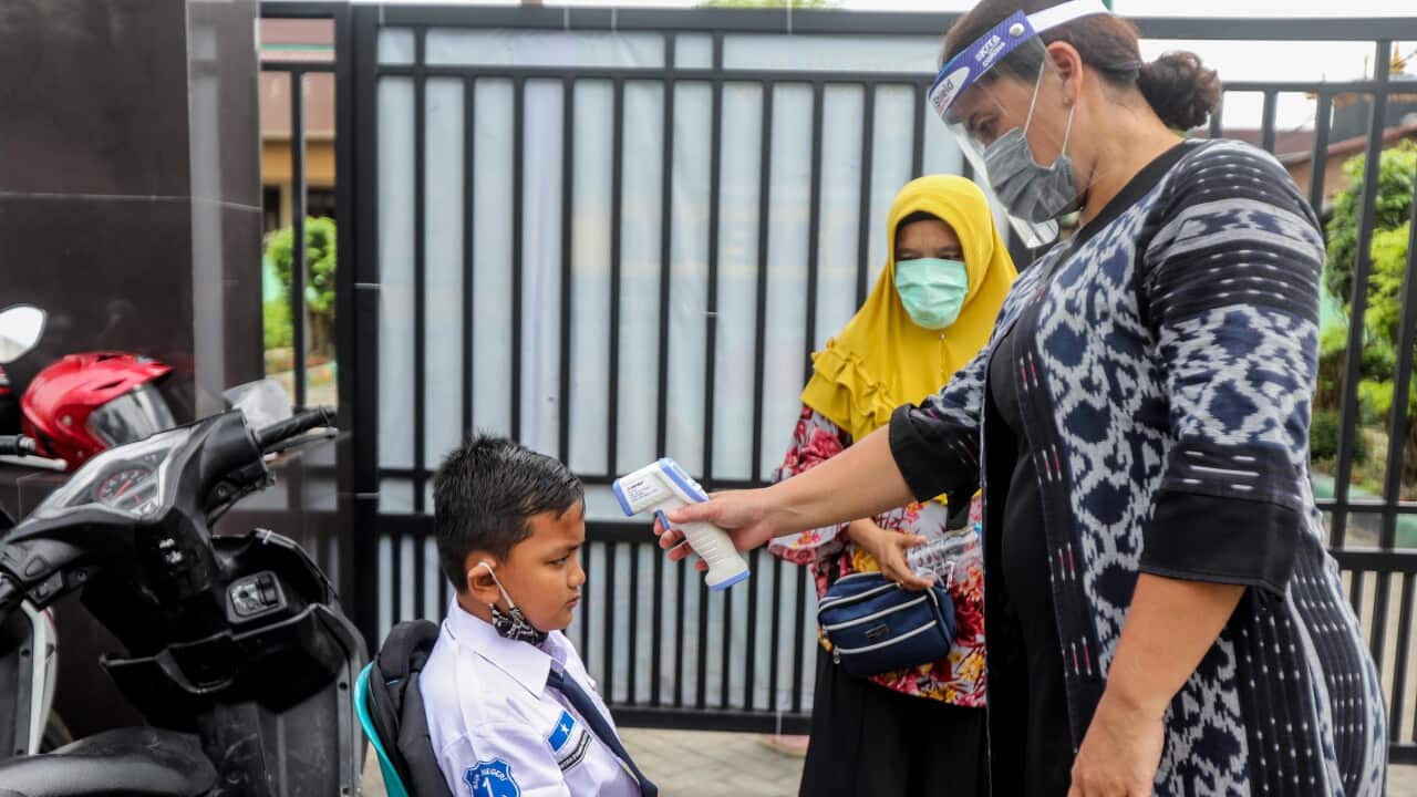 An Indonesian student gets his temperature measured on the first day of reopening schools in Medan, Indonesia.