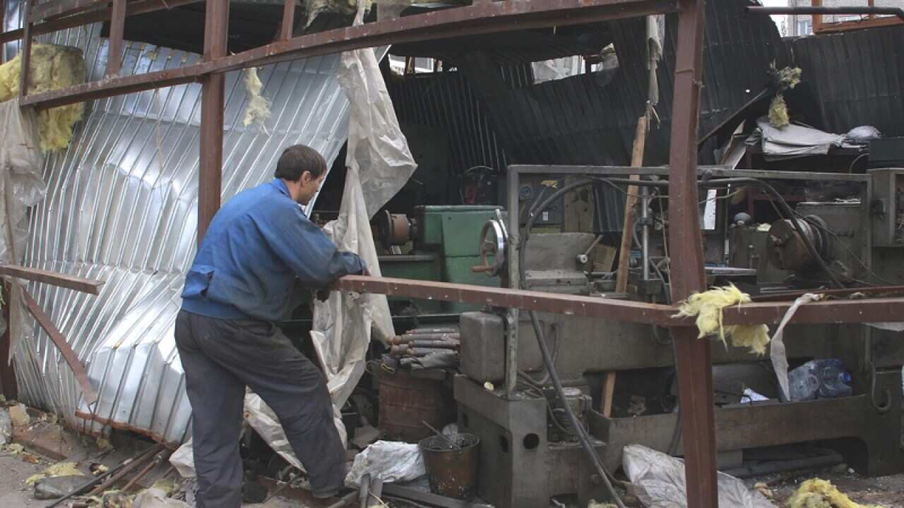 A man looks on a damaged factory in Ukraine