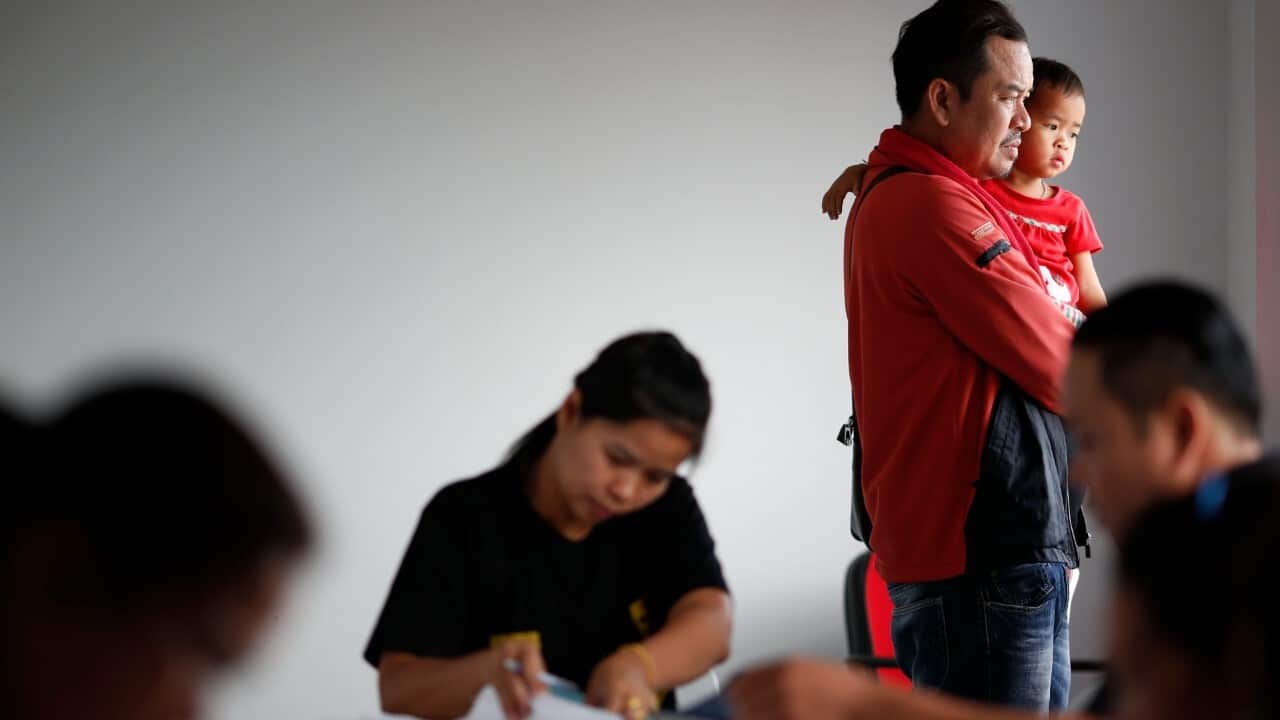 A Lao migrant worker, holds his daughter next to Thai employers during a registration drive at the Employment Office in Samut Sakhon province, Thailand (AAP Image - EPA - RUNGROJ YONGRIT)