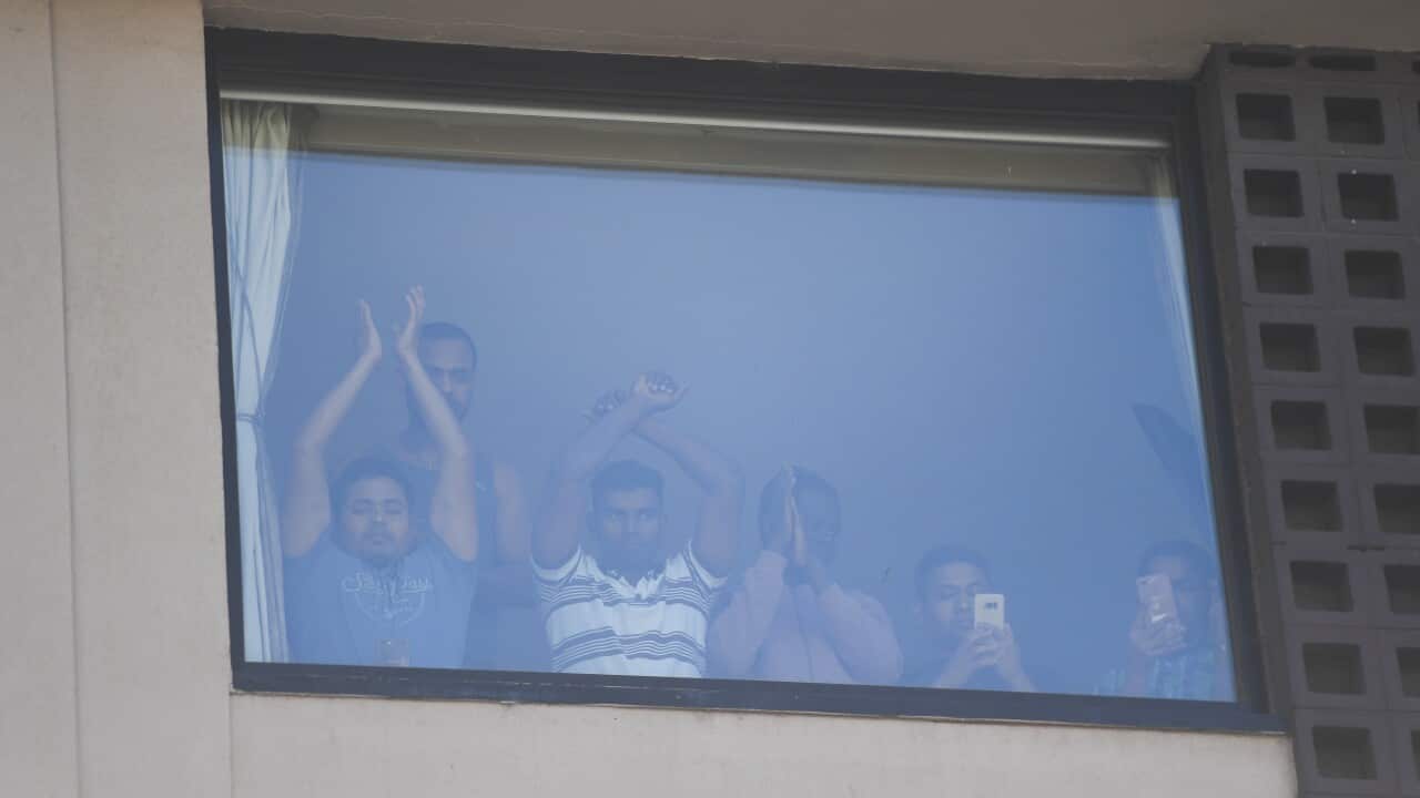 Refugees gesture towards protesters at the Park Hotel in Melbourne, Saturday, January 09, 2021. (AAP Image/Erik Anderson) NO ARCHIVING