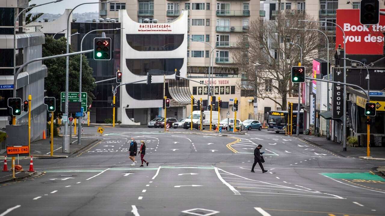 People cross nearly empty streets in the central business district of Auckland