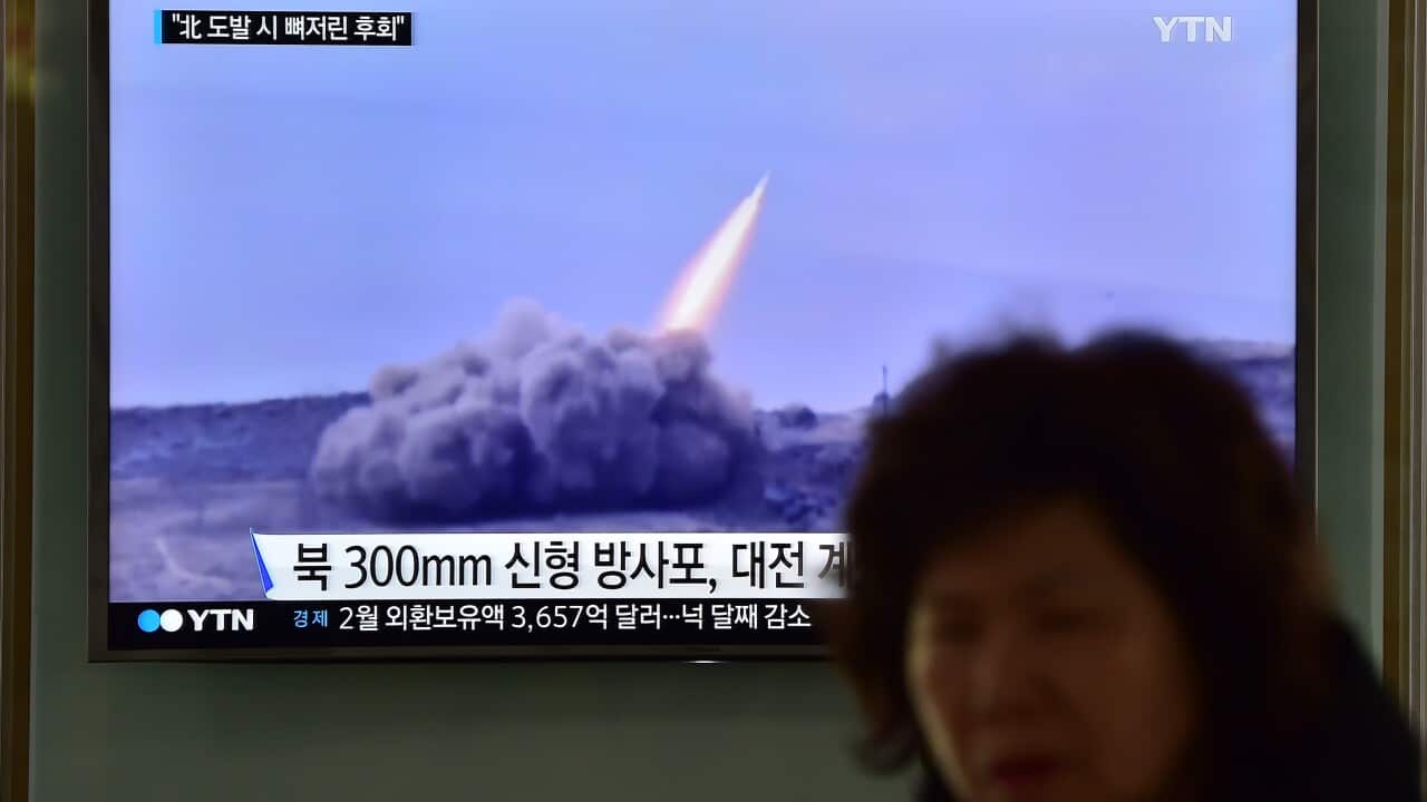 A public television screen showing file footage of a North Korean missile, at a railway station in Seoul.
