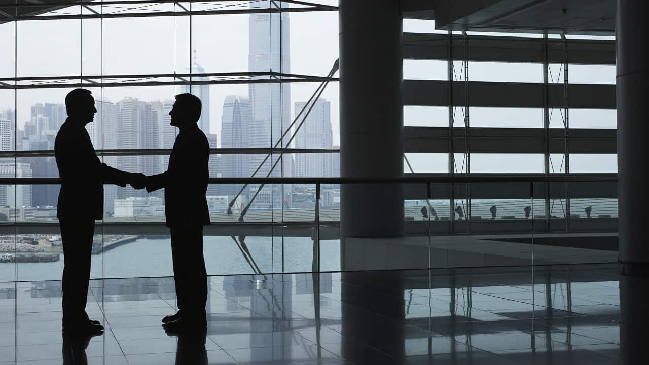 Silhouettes of two business men shaking hands