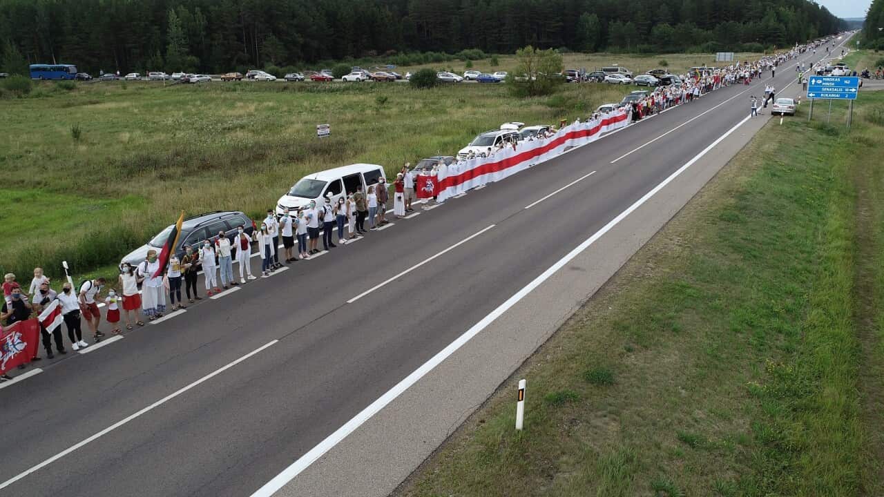 People hold hands, historical white-red-white flags of Belarus and flowers as they participate in the 'Freedom Way'