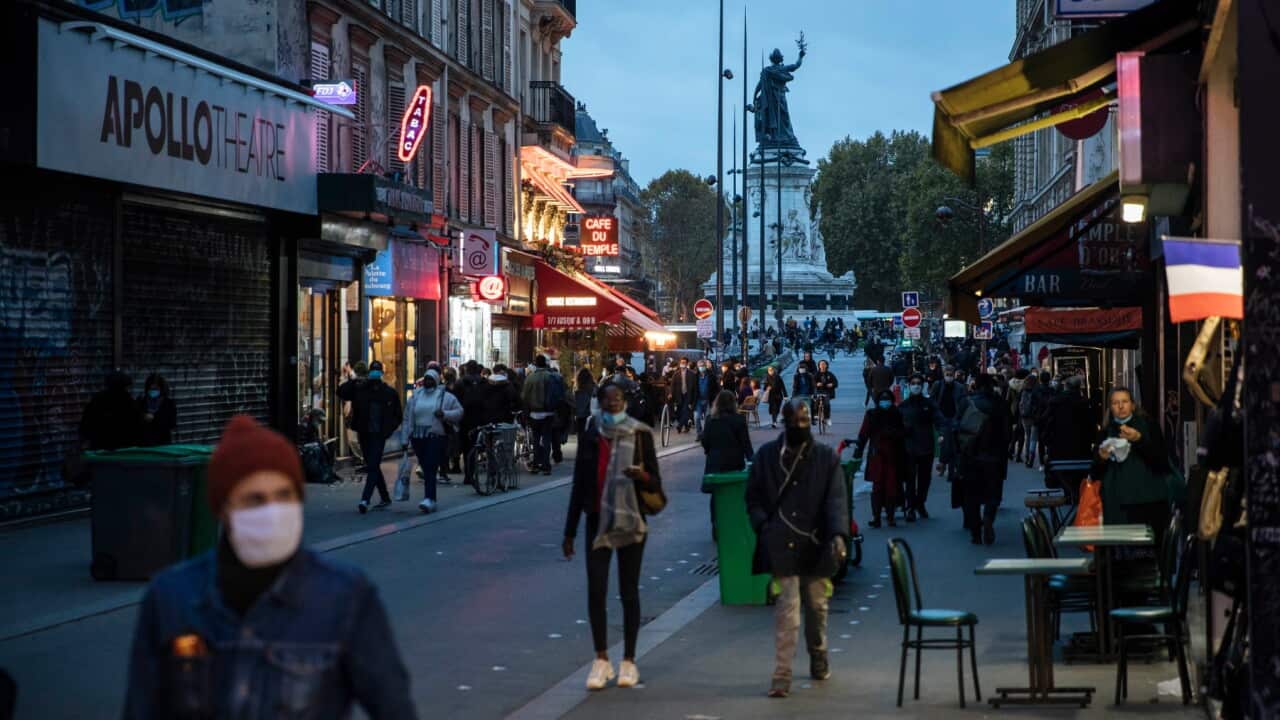 People wearing protective masks walk in a street of Paris