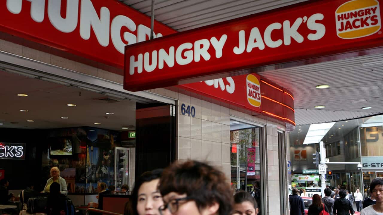 A couple walk past a Hungry Jack's fast food outlet in Sydney