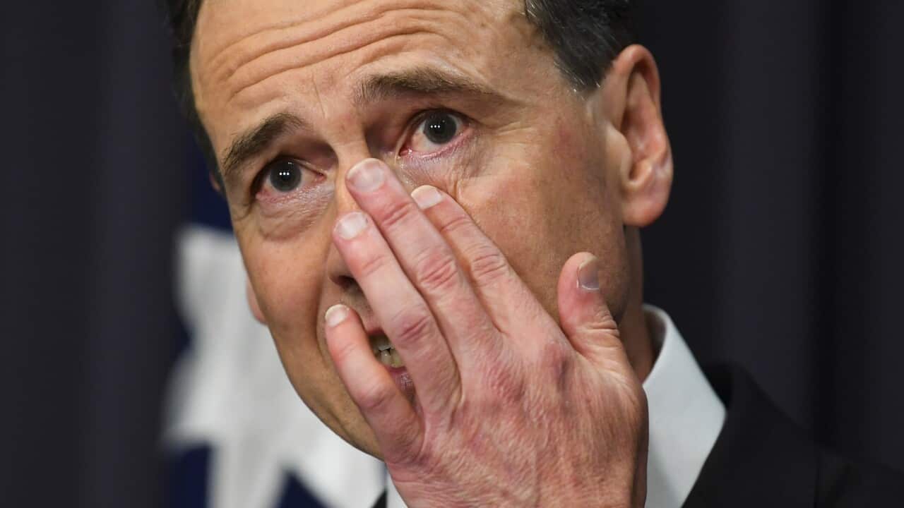 Health Minister Greg Hunt wipes away a tear during a press conference at Parliament House in Canberra
