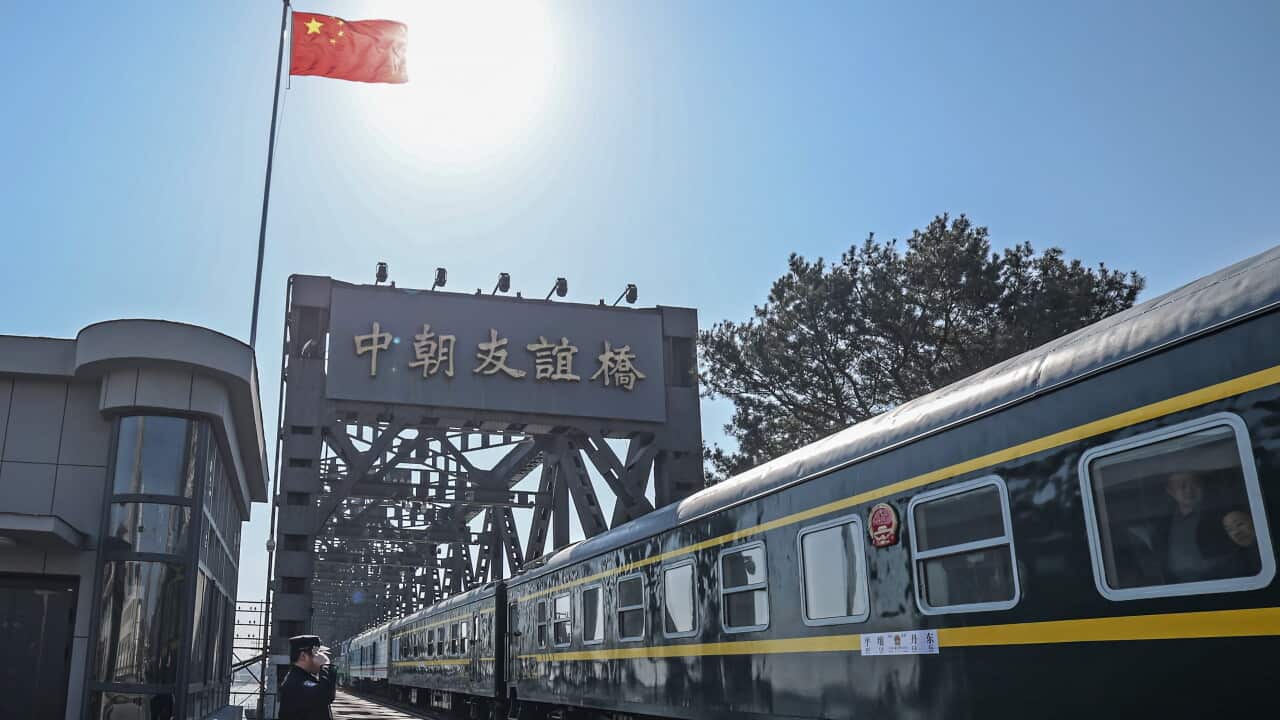 A train on a platform with Chinese characters indication it's in Dandong