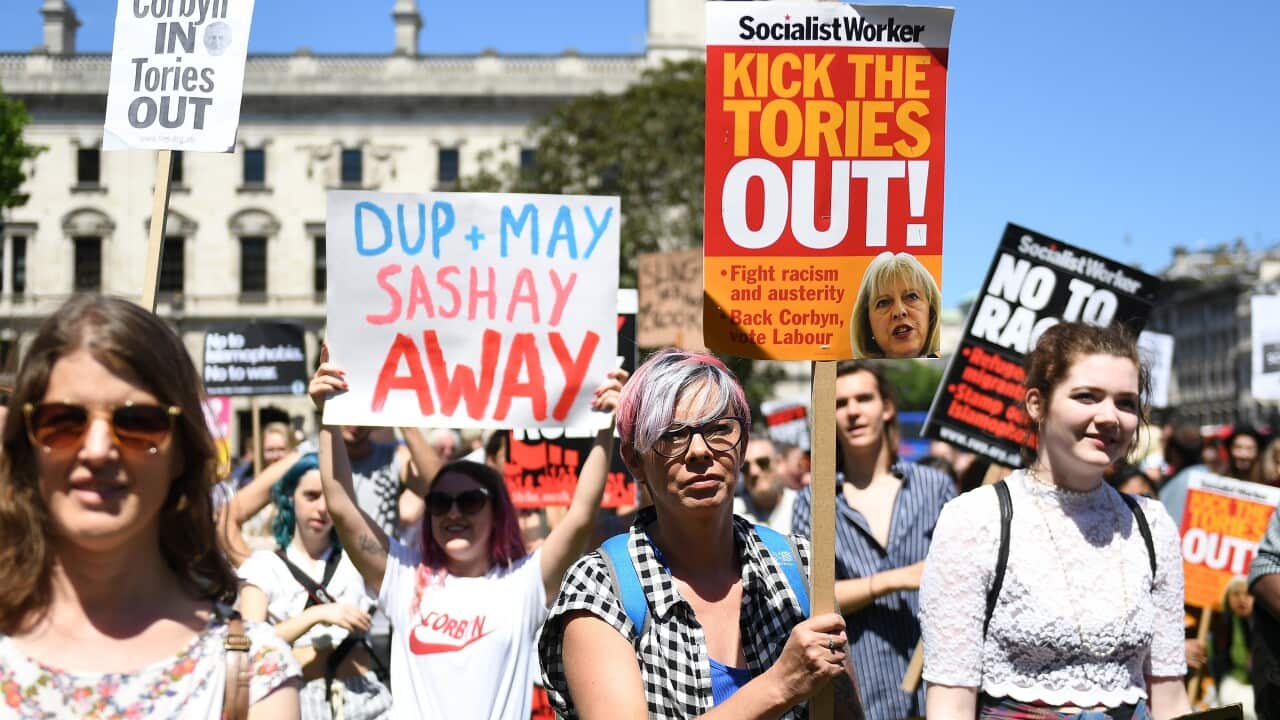 Protesters hold placards as they attend a demonstration against the Conservative party alliance with the DUP in Parliament Square