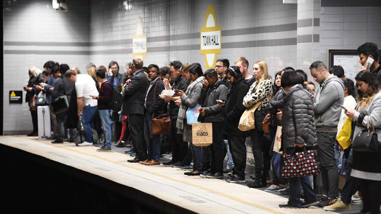 A large crowd of people waiting at a train station in Sydney.