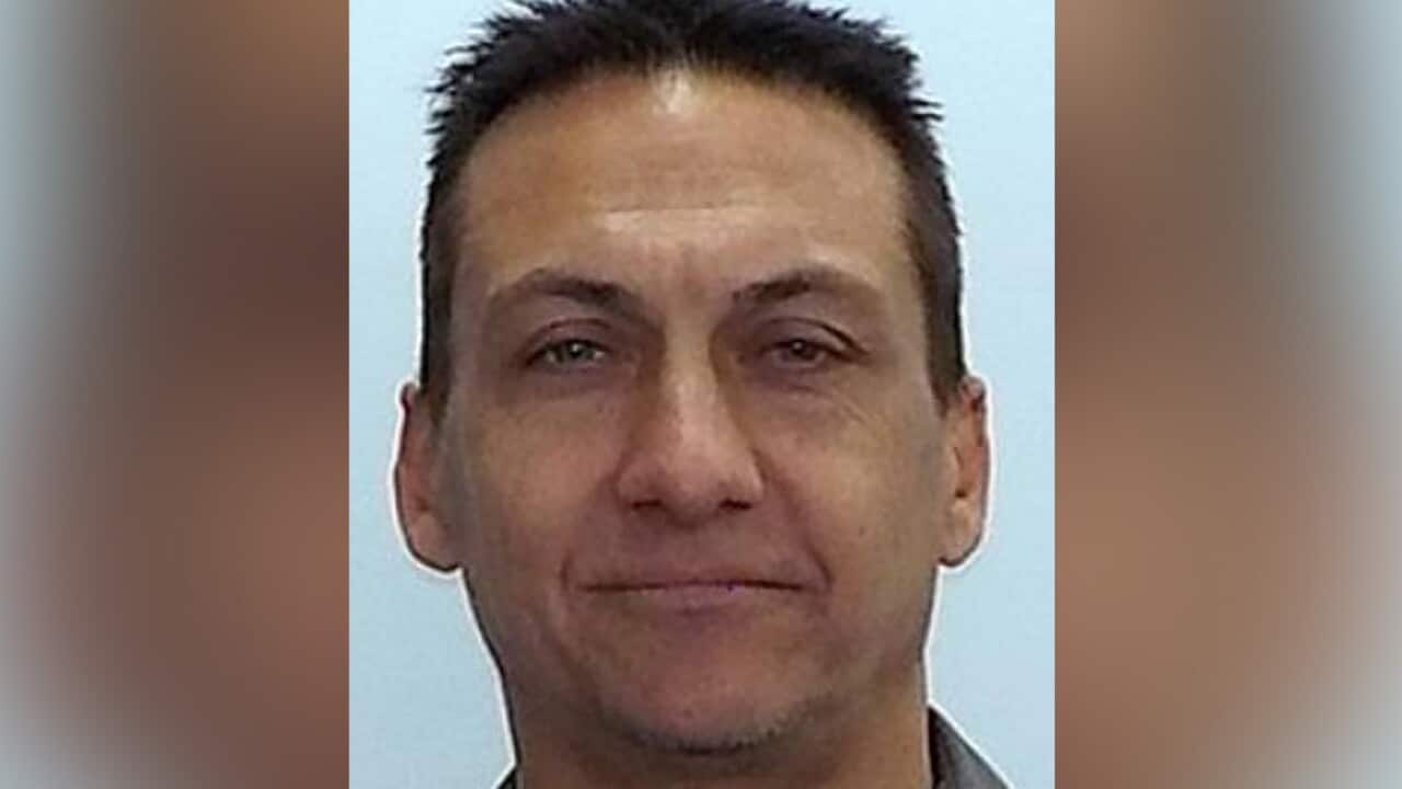 A head-and-shoulders portrait shows a middle-aged man with short, dark, spiky hair and a neutral expression against a light blue background.