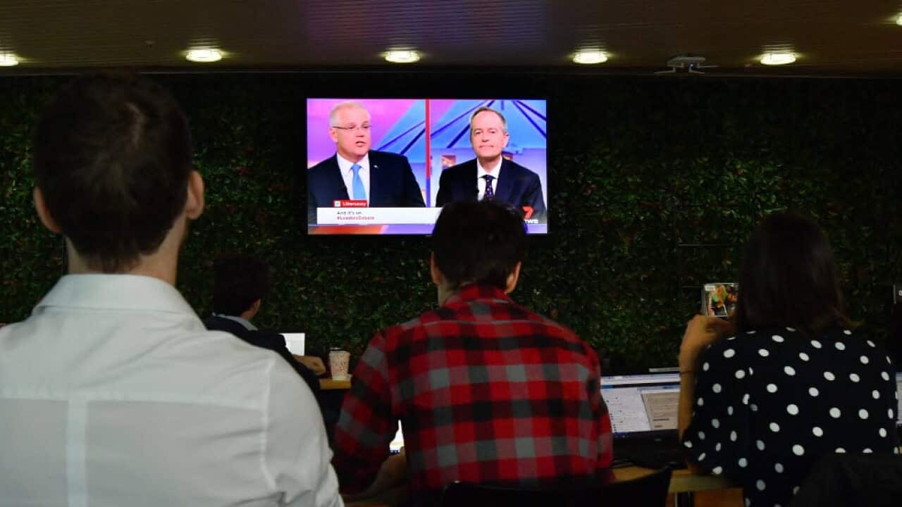 Journalists are seen watching a TV as the leaders debate (AAP)