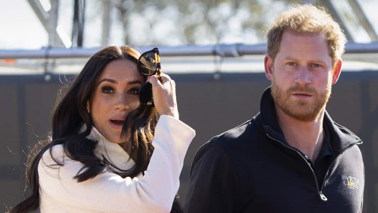 A woman hlding sunglasses and her husband standing next to her