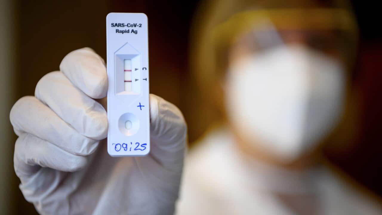 A health worker shows a positive SARS-CoV-2 Rapid Antigen Test from the Swiss multinational healthcare company Roche just after collecting a nose swab sample for a polymerase chain reaction (PCR) at the coronavirus testing facility of Unisante in Lausanne