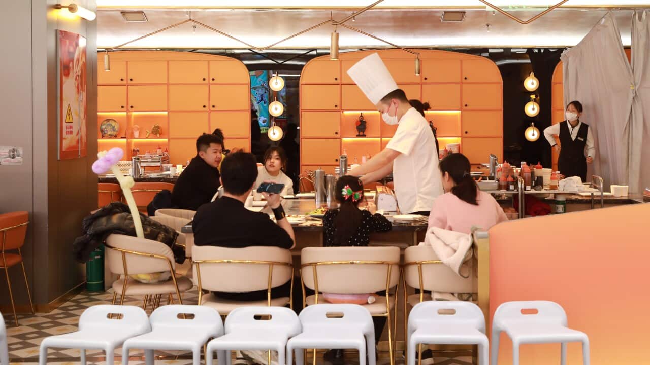People seated around a chef at a restuarant.
