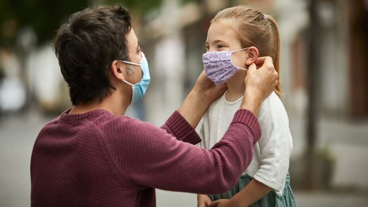 Father helps daughter with mask