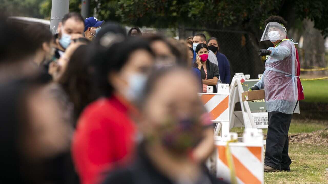 A volunteer interacts with people waiting in line to be tested for COVID-19 at a drive-in and walk up testing site in Los Angeles, California.