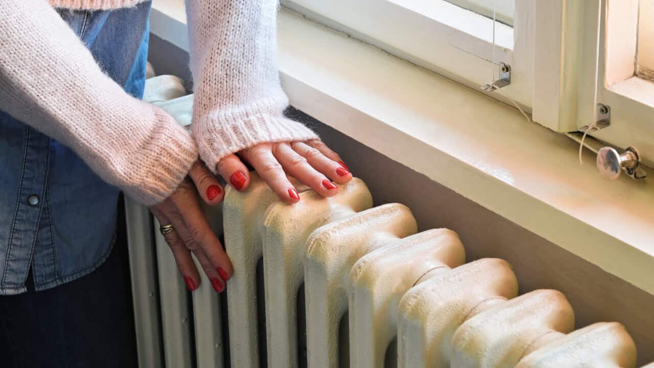 A woman touching a heater in her home.