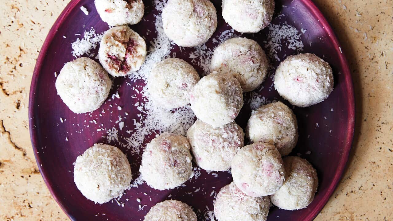 Pink-speckled strawgberry gum balls sit on a purple plate.