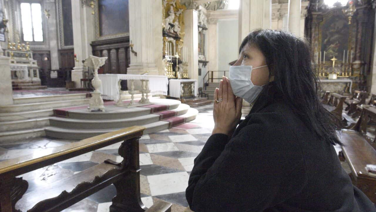 A worshipper prays with a mask on in Italy during the COVID-19 Crisis.